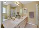 Bathroom with double vanity, large mirror, and walk-in shower at 1213 El Esparza Ln, The Villages, FL 32159