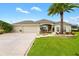 Tan colored, single-story house with a three-car garage and a palm tree in the front yard at 3520 Quietwoods Dr, The Villages, FL 32163