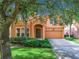 Two-story house with orange exterior, two-car garage, and lush landscaping at 426 Orange Cosmos Blvd, Davenport, FL 33837