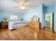 Main bedroom with light blue walls, hardwood floors, and access to another room at 5430 Sir Churchill Dr, Leesburg, FL 34748