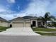 Tan house with three car garage and solar panels at 1316 Water Willow Dr, Groveland, FL 34736