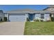 Single-story home with light blue exterior, two-car garage and landscaping at 74 Polermo Ave, Saint Cloud, FL 34771