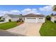 Two-car garage, landscaped yard, and a driveway at 2403 Carriage Hill Way, The Villages, FL 32162