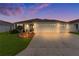 Well-lit home with a two-car garage at dusk at 2403 Carriage Hill Way, The Villages, FL 32162