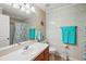 Bathroom with tiled shower, vanity sink, and teal towels at 1039 Sandhill St, Groveland, FL 34736