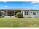 House back view showing covered patio, lush landscaping, and AC unit at 5500 Belle Terre Dr, Leesburg, FL 34748