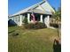 Light blue house with a covered porch, red shutters, and a metal roof at 104 Turtle Run, Umatilla, FL 32784