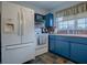 White appliances and blue cabinets in this galley-style kitchen at 4988 County Road 155, Wildwood, FL 34785