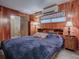 Bedroom with wood paneled walls, a large bed, and window at 4988 County Road 155, Wildwood, FL 34785