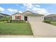 Tan house with red shutters, two-car garage and manicured lawn at 5120 Tanzanite Dr, Mount Dora, FL 32757