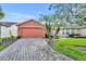 Single-story house with orange exterior, paver driveway, and landscaping at 540 Grand Canal Dr, Kissimmee, FL 34759