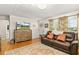 Living room with hardwood floors, a brown leather sofa, and a large flat-screen TV at 326 N Sunset Dr, Mount Dora, FL 32757