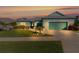 Evening view of teal home with landscaping and driveway at 25304 Forest Oak Ct, Leesburg, FL 34748