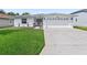 White house with gray roof, two-car garage, and well-manicured lawn at 32857 Timberwood Dr, Leesburg, FL 34748