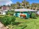 Charming teal house with lush landscaping, a spacious yard, and a detached shed at 1559 Lakeshore Dr, Eustis, FL 32726