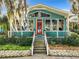Teal home with a red door, lush landscaping, and white railings at 1559 Lakeshore Dr, Eustis, FL 32726