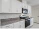 White kitchen cabinets and granite countertops with stainless steel appliances at 1496 Mirabella Cir, Davenport, FL 33897
