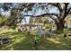 Spacious backyard with large oak tree, seating area, and lush landscaping at 218 Ann St, Lady Lake, FL 32159