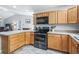 Modern kitchen with wood cabinets, black appliances, and an island at 3358 Quail Hollow Ct, The Villages, FL 32163