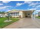 Yellow manufactured home with carport and lush landscaping at 1704 Pebble Beach Ln, Lady Lake, FL 32159