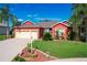 Red house with three-car garage and manicured lawn at 25611 Maurepas Ln, Leesburg, FL 34748