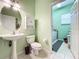 Small bathroom with white pedestal sink and toilet, adjacent to laundry at 25611 Maurepas Ln, Leesburg, FL 34748