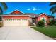 Red house with three-car garage, mature landscaping, and a large driveway at 25611 Maurepas Ln, Leesburg, FL 34748