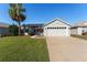 Single-story house with a two-car garage and lush lawn at 1312 Landeros Ln, The Villages, FL 32159