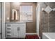 Bathroom with white vanity, gray tiled shower, and a window with blinds at 9832 Florida Boys Ranch Rd, Clermont, FL 34711