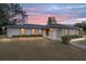 Single-story house with a red door and landscaped yard at dusk at 2101 Sw 3Rd St, Ocala, FL 34471