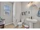 Clean bathroom with pedestal sink, toilet, and a large round mirror at 2298 Raven Ridge Rd, Minneola, FL 34715