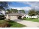 House exterior featuring a stone and beige facade, two-car garage, and manicured lawn at 34932 Golden Tree Dr, Leesburg, FL 34788