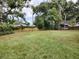 Large grassy backyard with mature trees and a wooden fence at 351 W 10Th Ave, Mount Dora, FL 32757