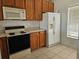 Kitchen with wood cabinets, refrigerator, and window with blinds at 652 Chelsea Dr, Davenport, FL 33897