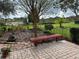 Lovely patio with brick pavers, red bench, and flower garden at 21630 King Henry Ave, Leesburg, FL 34748