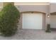 White garage door with brick pavers and lush green shrubbery at 3406 Soho St # 102, Orlando, FL 32835