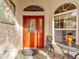 Welcoming front entry featuring a red door and patio seating at 877 Winifred Way, The Villages, FL 32162