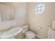 Simple bathroom with pedestal sink, toilet, and unique window at 25114 Meriweather Rd, Leesburg, FL 34748