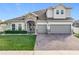 Two-story house with stone accents, three-car garage, and manicured lawn at 405 Amola Way, Howey In The Hills, FL 34737