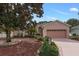 House exterior featuring a pink facade, two-car garage, and landscaping at 4803 Sawgrass Lake Cir, Leesburg, FL 34748