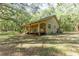 Tan house exterior with a large wrap-around porch and surrounding trees at 9442 Cr 674, Bushnell, FL 33513