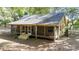 Tan house exterior with a screened porch, wooden deck, and surrounding trees at 9442 Cr 674, Bushnell, FL 33513