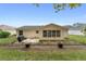Home's back features a patio, grill, and a well-manicured lawn at 1612 Staunton St, The Villages, FL 32162