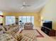 Spacious living room with tiled floor, floral sofas, and a view of the lanai at 4634 Summerbridge Cir, Leesburg, FL 34748