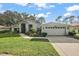 Single-story home with a two-car garage and well-manicured lawn at 5533 Grove Mnr, Lady Lake, FL 32159