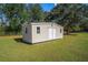 Tan shed with double doors in a grassy yard at 7921 Jacksons River Rd, Leesburg, FL 34788