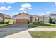 One-story home with brown garage door, landscaping, and brick pavers at 29549 Caspian St, Leesburg, FL 34748