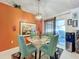 Bright dining room with glass table and teal chairs, adjacent to the kitchen at 31748 Parkdale Dr, Leesburg, FL 34748