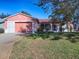 Pink single-story house with attached garage and landscaped lawn at 33236 Grand Cypress Way, Leesburg, FL 34748