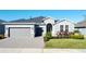 Gray one-story house with a gray three-car garage and well-manicured lawn at 409 Alcove Dr, Groveland, FL 34736